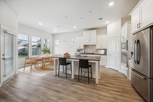 29035 Nectar Island Ln, Katy, TX 77494 - kitchen featuring stainless steel appliances, tasteful backsplash, a kitchen breakfast bar, light wood finished floors, and recessed lighting