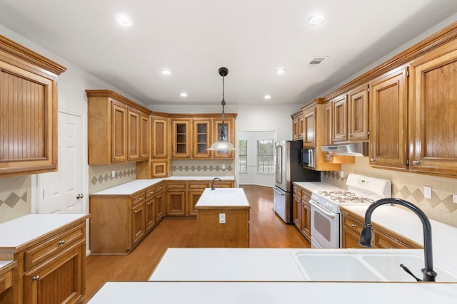 kitchen featuring under cabinet range hood, visible vents, a sink, and gas range gas stove