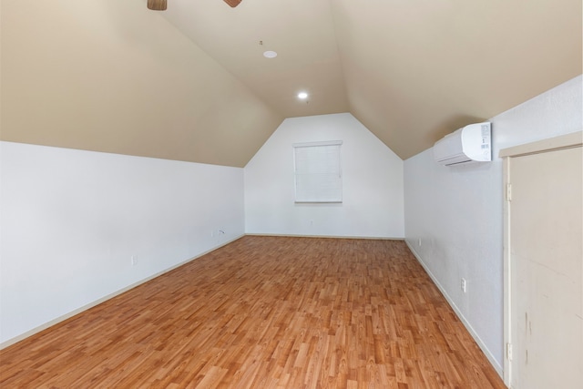 bonus room with baseboards, ceiling fan, light wood finished floors, vaulted ceiling, and a wall unit AC