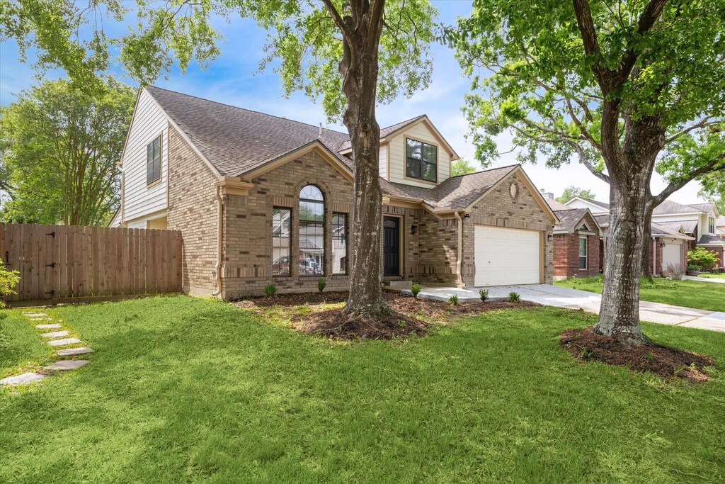1223 Berkeley Lake Ln, Houston, TX 77062 - traditional home with driveway, an attached garage, a front lawn, brick siding, and fence