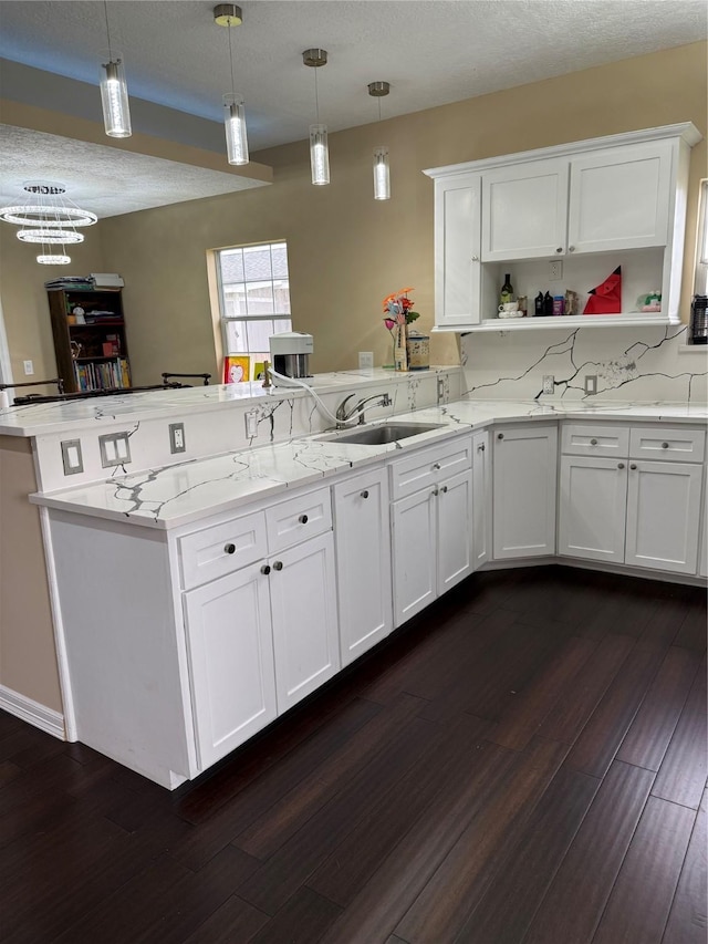 kitchen featuring a peninsula, white cabinetry, open shelves, dark wood-style flooring, and a sink