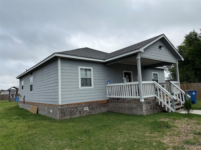 rear view of property with a yard, a porch, crawl space, and roof with shingles