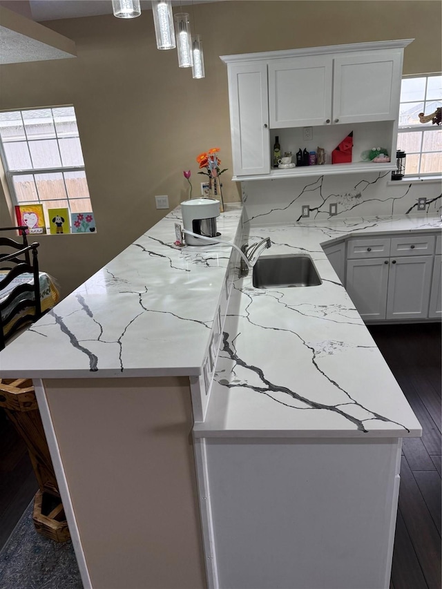 kitchen with a sink, white cabinets, open shelves, and a peninsula