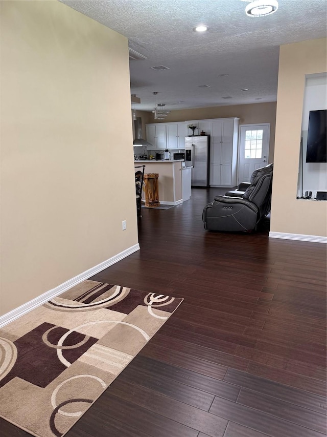 corridor featuring a textured ceiling, baseboards, and dark wood finished floors