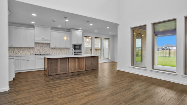kitchen featuring light countertops, built in microwave, stovetop, dark wood-style floors, and decorative backsplash