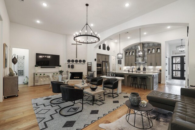 2514 Heritage Park Dr, Missouri City, TX 77459 - living room featuring high vaulted ceiling, arched walkways, an inviting chandelier, and light wood-style flooring