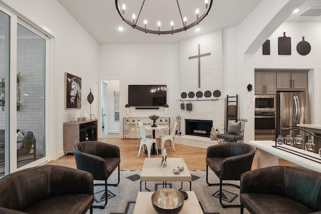 2514 Heritage Park Dr, Missouri City, TX 77459 - living area featuring light wood-style flooring, visible vents, a chandelier, a fireplace, and a towering ceiling