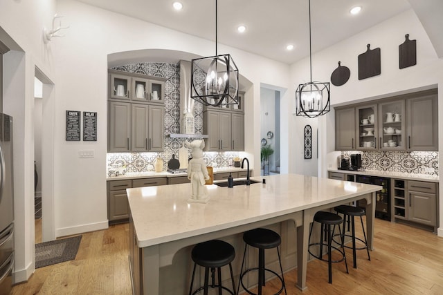2514 Heritage Park Dr, Missouri City, TX 77459 - kitchen with light wood-style flooring, a sink, gray cabinetry, an inviting chandelier, and backsplash