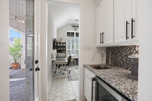 2514 Heritage Park Dr, Missouri City, TX 77459 - interior space featuring beverage cooler, decorative backsplash, a sink, baseboards, and lofted ceiling