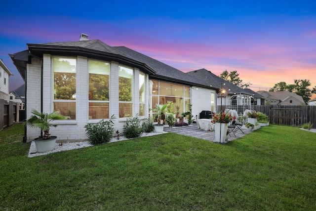 2514 Heritage Park Dr, Missouri City, TX 77459 - back of house at dusk with brick siding, a yard, fence private yard, and a patio area