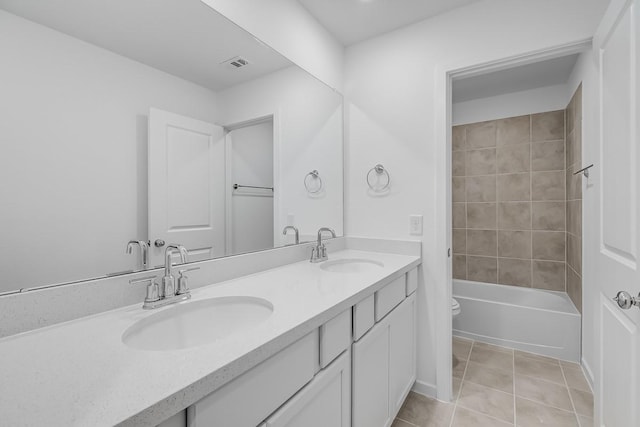 bathroom with double vanity, tile patterned flooring, toilet, and a sink