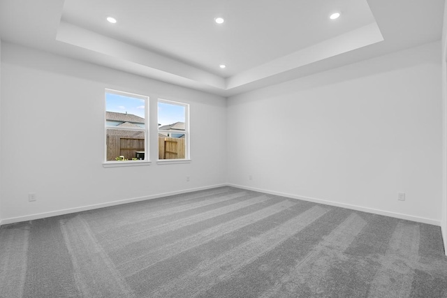 unfurnished room with recessed lighting, dark colored carpet, and a raised ceiling