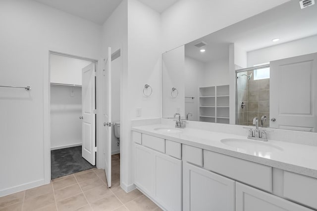 full bath featuring a walk in closet, double vanity, a stall shower, and a sink