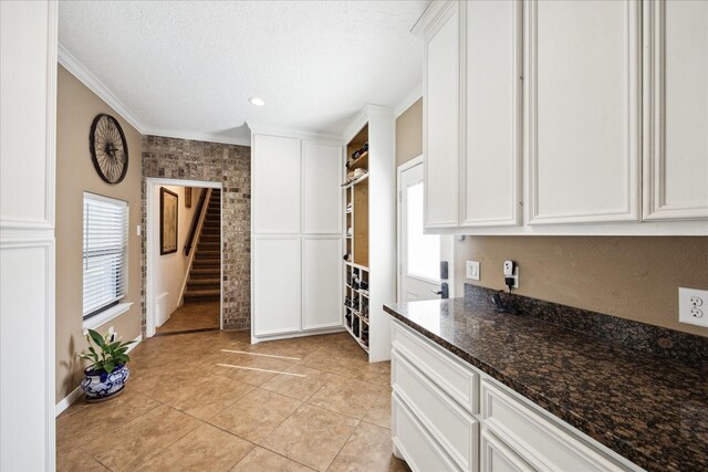 3650 Ward Bend Rd, Sealy, TX 77474 - kitchen featuring crown molding, dark stone counters, white cabinets, light tile patterned flooring, and baseboards