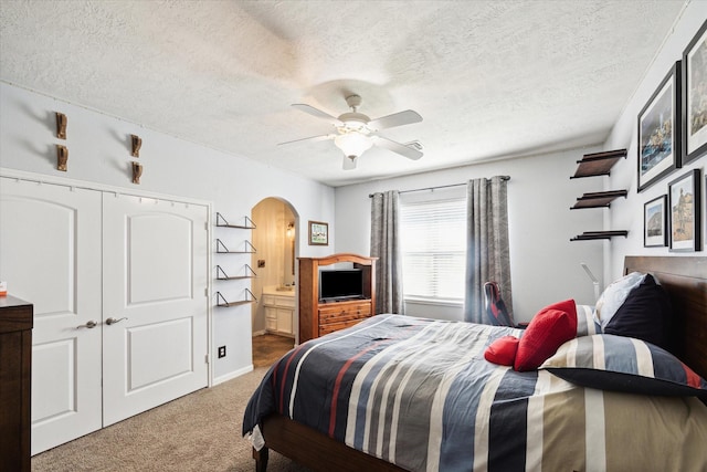 3650 Ward Bend Rd, Sealy, TX 77474 - carpeted bedroom with a closet, ensuite bathroom, a textured ceiling, ceiling fan, and arched walkways