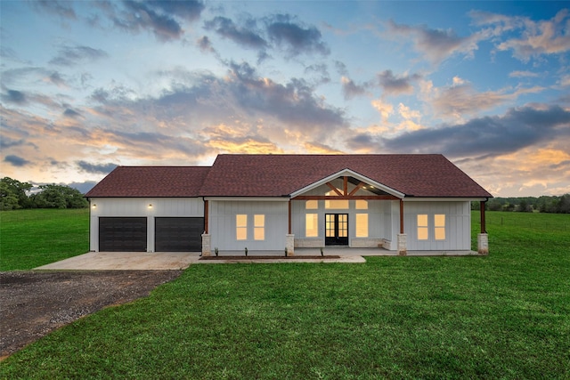 view of front facade with a garage, french doors, driveway, and a front yard