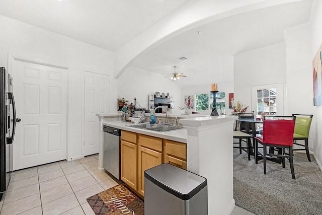 kitchen featuring stainless steel dishwasher, light tile patterned floors, arched walkways, a ceiling fan, and a sink