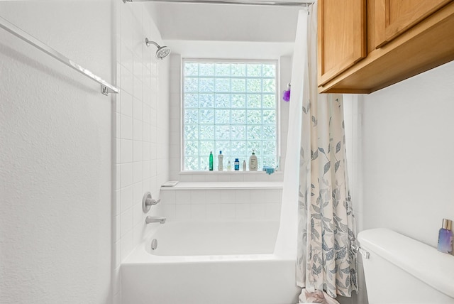 full bathroom with toilet, shower / tub combo, a healthy amount of sunlight, and a textured wall