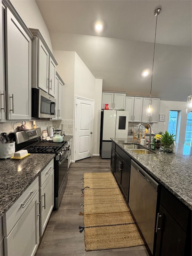 835 Sarasota Shore Dr, Katy, TX 77493 - kitchen featuring lofted ceiling, stainless steel appliances, dark stone countertops, a sink, and dark wood-style flooring
