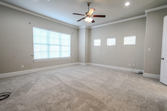 unfurnished room featuring a ceiling fan, light colored carpet, baseboards, and ornamental molding