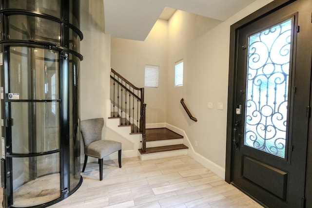 foyer entrance with stairway, light wood-style flooring, and baseboards