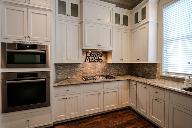 kitchen featuring tasteful backsplash, glass insert cabinets, white cabinets, and appliances with stainless steel finishes