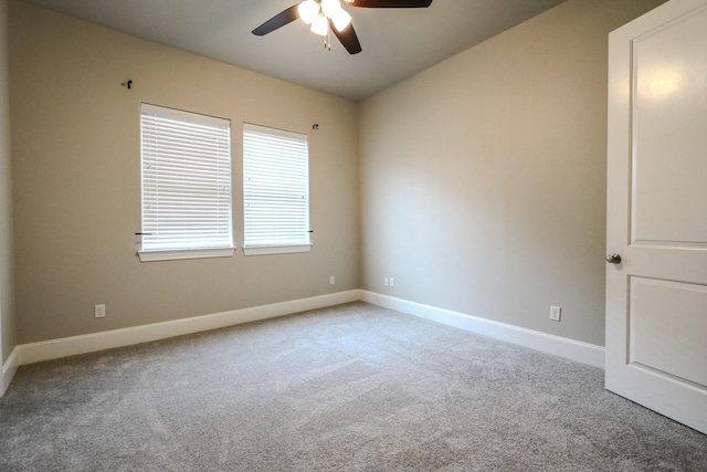 carpeted spare room with baseboards and a ceiling fan