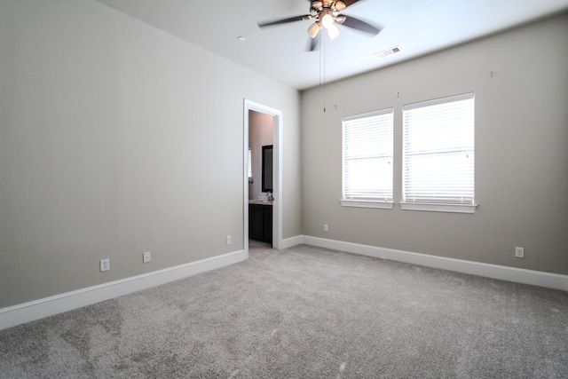 empty room featuring baseboards, visible vents, light colored carpet, and a ceiling fan