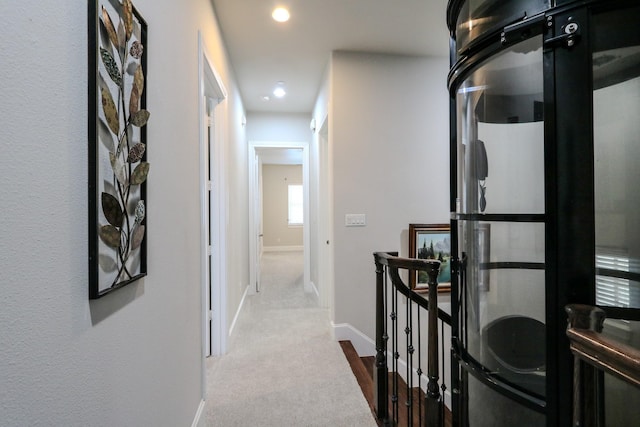 hall with recessed lighting, an upstairs landing, and baseboards