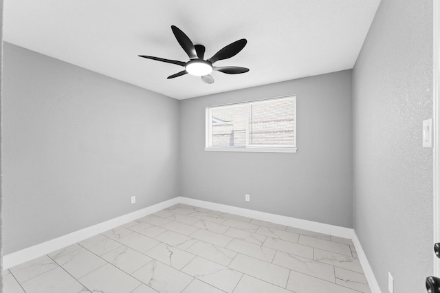 empty room with baseboards, marble finish floor, and a ceiling fan
