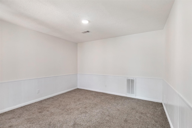 spare room featuring a textured ceiling, carpet floors, and visible vents