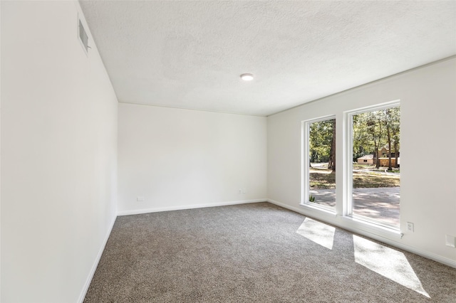 carpeted spare room with visible vents, baseboards, and a textured ceiling
