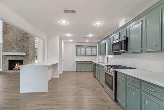 kitchen featuring baseboards, stainless steel appliances, light wood finished floors, and light countertops