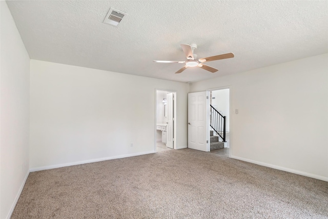 carpeted empty room featuring a textured ceiling, visible vents, baseboards, and ceiling fan
