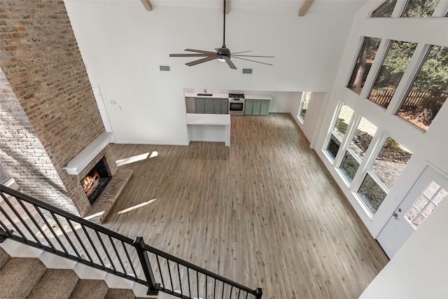 unfurnished living room with baseboards, a towering ceiling, wood finished floors, a warm lit fireplace, and stairway