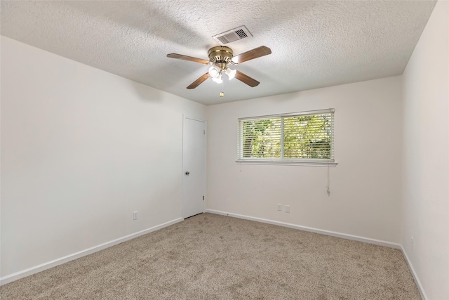empty room featuring visible vents, a textured ceiling, ceiling fan, and light colored carpet