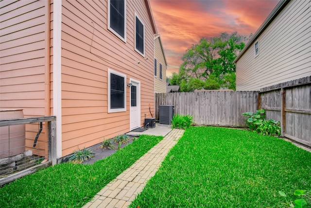 yard at dusk featuring cooling unit and a fenced backyard