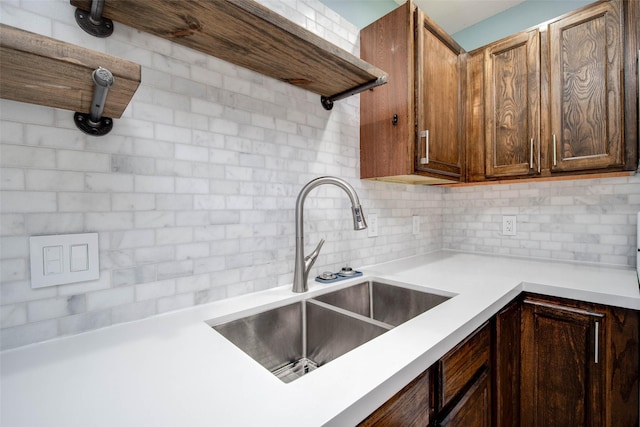 kitchen featuring a sink, backsplash, light countertops, and open shelves