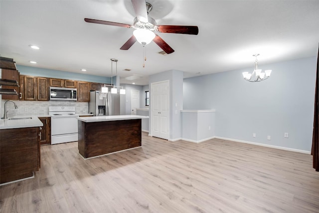 kitchen with a sink, light countertops, light wood-type flooring, stainless steel appliances, and a kitchen island