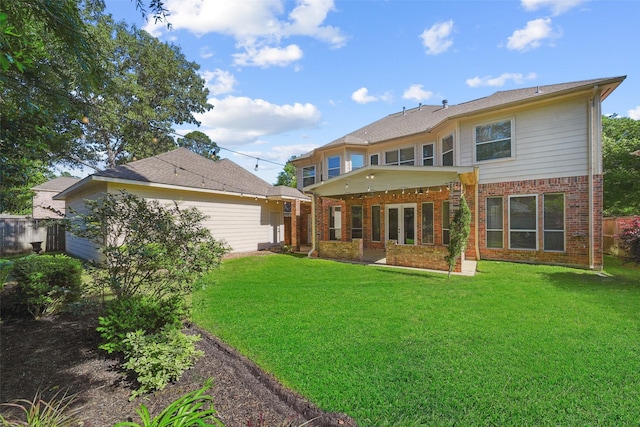 rear view of property with brick siding, fence, and a yard