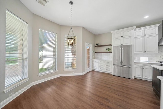 kitchen featuring high end refrigerator, open shelves, light countertops, dark wood finished floors, and visible vents