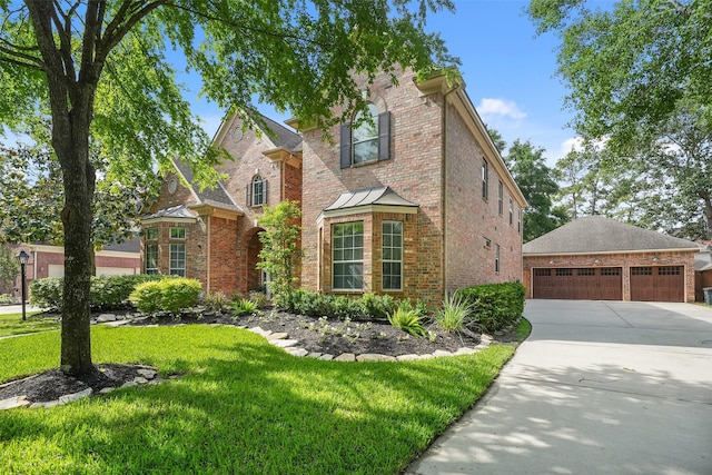 traditional-style home featuring brick siding, a detached garage, a front yard, and concrete driveway