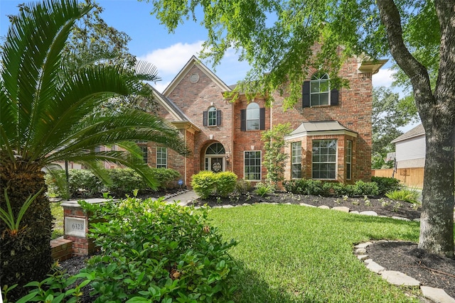 view of front of home featuring brick siding, a front lawn, and fence