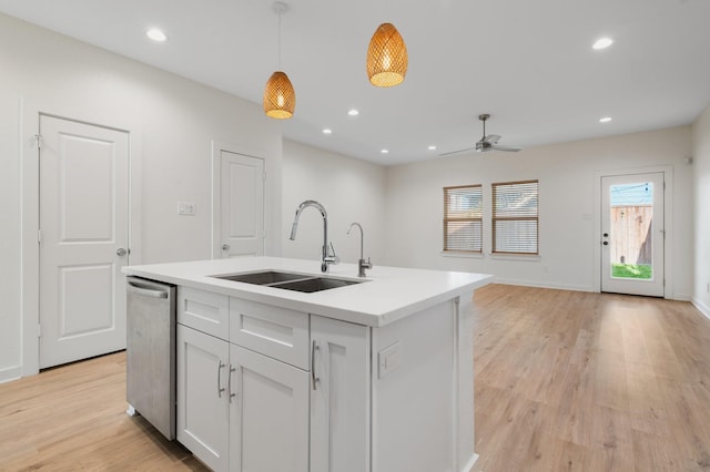 kitchen with ceiling fan, hanging light fixtures, a sink, light wood finished floors, and light countertops