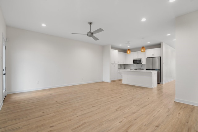 unfurnished living room with light wood-style floors, baseboards, ceiling fan, recessed lighting, and a sink