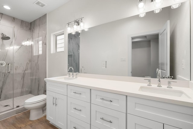 bathroom with toilet, visible vents, a marble finish shower, and a sink