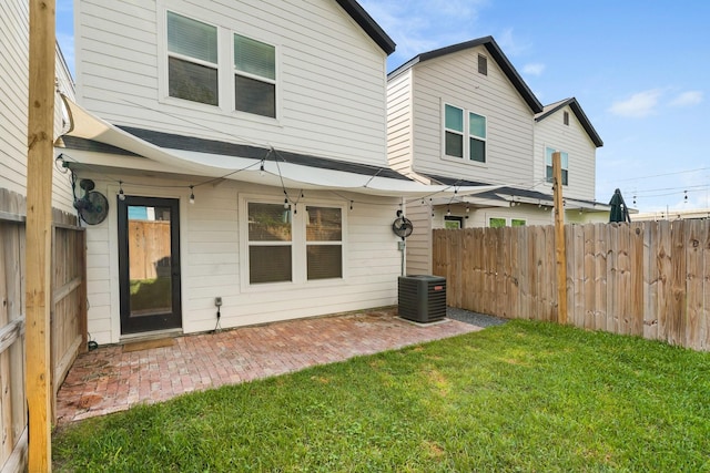 rear view of house featuring a patio, a fenced backyard, central AC, and a yard