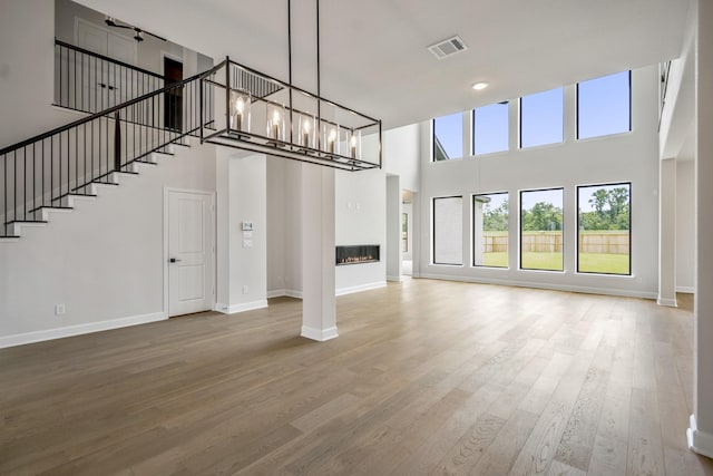 9618 Leafgate Ct, Missouri City, TX 77459 - unfurnished living room with a high ceiling, baseboards, wood finished floors, stairs, and a glass covered fireplace