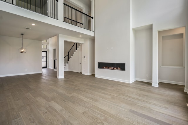 9618 Leafgate Ct, Missouri City, TX 77459 - unfurnished living room featuring a glass covered fireplace, wood finished floors, baseboards, a high ceiling, and stairway