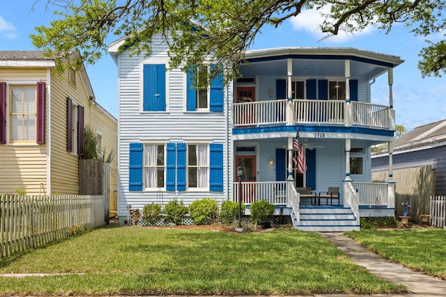 view of front facade with a porch, fence, a balcony, and a front yard